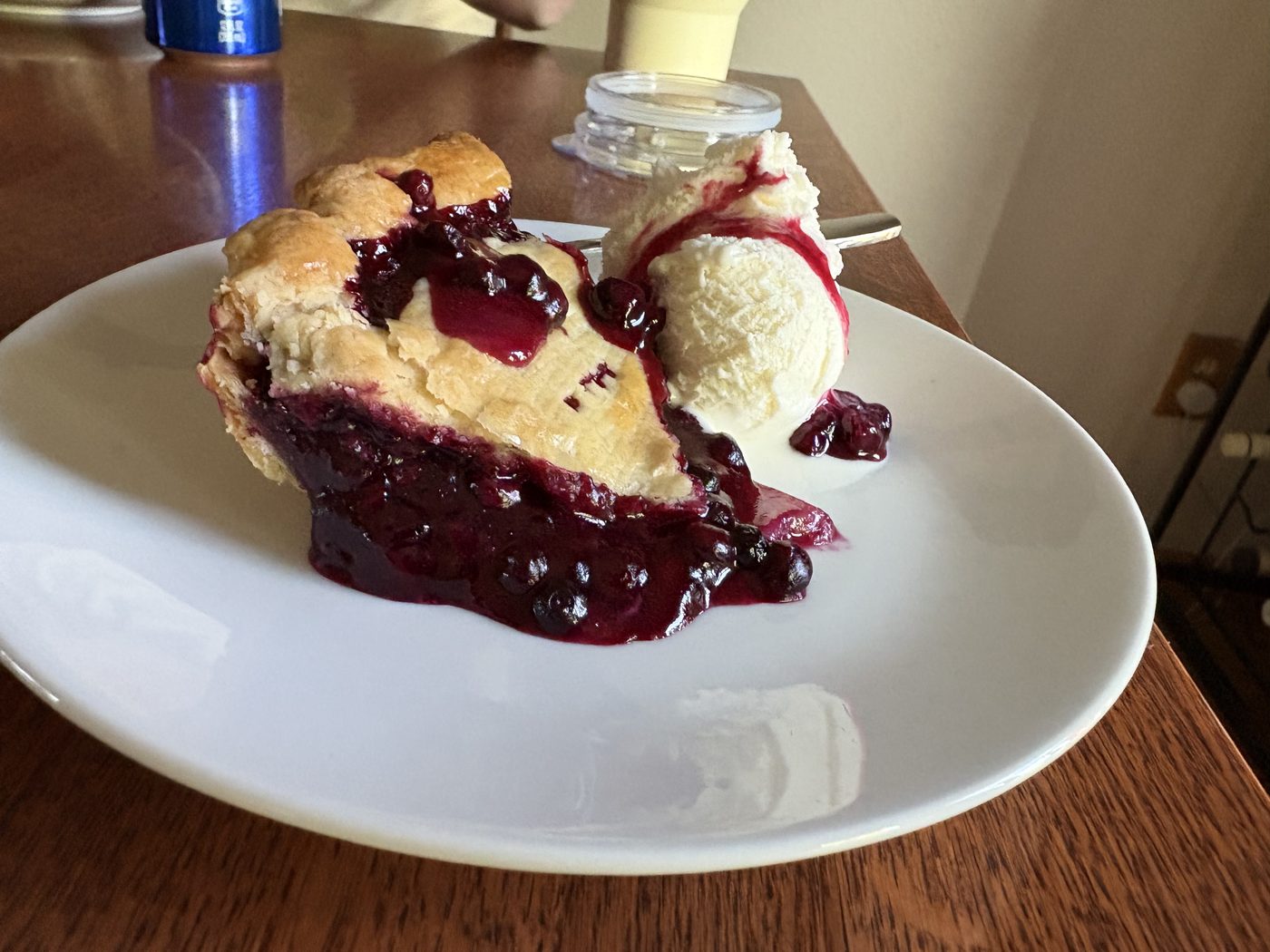 A slice of huckleberry pie with a scoop of vanilla ice cream