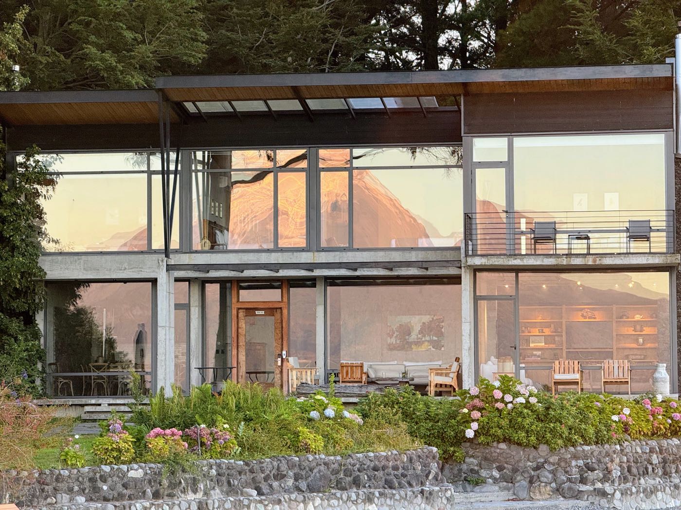 Hotel AWA, a modern glass and wood building, lit up at dusk